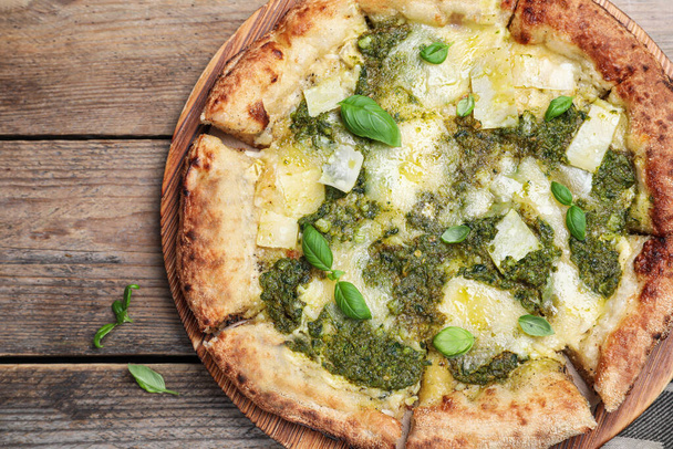 Delicious pizza with pesto, cheese and basil on wooden table, flat lay - Fotografie, Obrázek