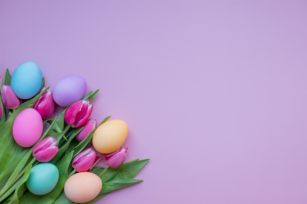 Ostereier und Tulpenblüten auf rosa Hintergrund. Osterkarte mit verzierten Eiern und Tulpenblumen. - Foto, Bild