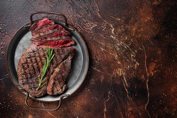 Grilled Medium Rare top sirloin beef steak or rump steak on a steel tray. Dark background. Top view. Copy space - Foto, afbeelding