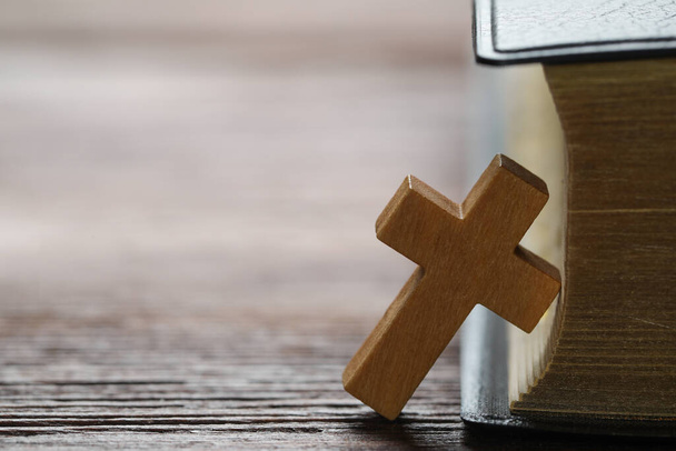 Houten Christelijk kruis en Bijbel op tafel, close-up. Ruimte voor tekst - Foto, afbeelding