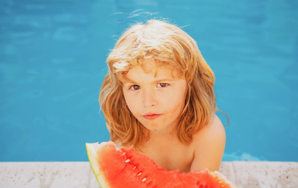 Child boy eats watermelon near the pool. Kid with water melon. Kids summer activities. - Fotoğraf, Görsel