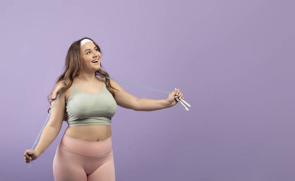 Surprised happy excited plus size european young lady in sportswear with open mouth and skipping rope - Foto, afbeelding