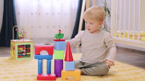 χαριτωμένο μικρό αγόρι παίζει με μπλοκ στο παιδικό δωμάτιο - Πλάνα, βίντεο