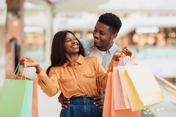 Porträt eines aufgeregten schwarzen Paares, das mit Einkaufstüten spaziert - Foto, Bild