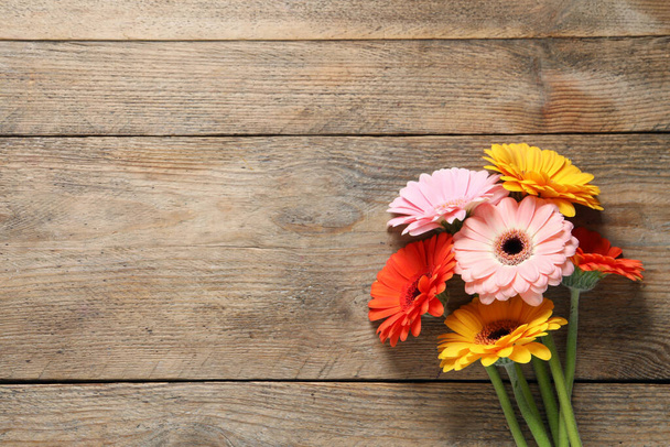 Beautiful colorful gerbera flowers on wooden table, flat lay. Space for text - Foto, Bild