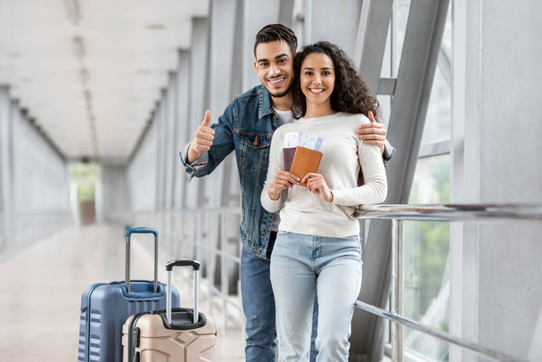 Anuncio de viajes. Feliz joven pareja árabe posando en el aeropuerto - Foto, Imagen