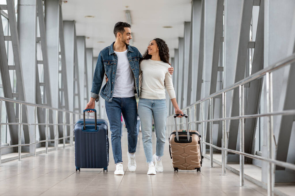 Gemeinsam reisen. Glückliche junge arabische Eheleute gehen mit Gepäck am Flughafen-Terminal, - Foto, Bild