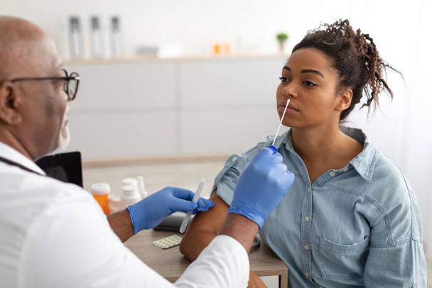 Médecin prélevant l'échantillon de test PCR de femme noire potentiellement infectée - Photo, image