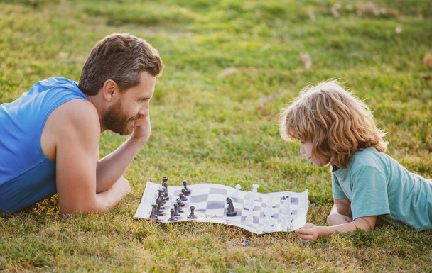 Father and son playing chess spending time together outdoor. - Фото, зображення