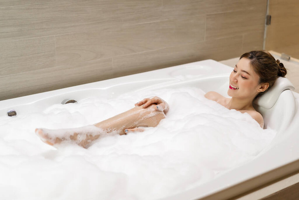 young woman relaxing and takes bubble bath in bathtub with foam - Foto, Imagen