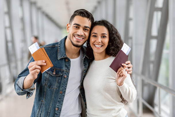 Viajantes felizes. Casal árabe jovem com passaportes e bilhetes posando no aeroporto - Foto, Imagem
