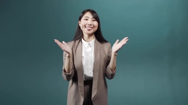 Una donna attraente asiatica che indossa un abito formale è in piedi e applaudendo guardando la fotocamera - Filmati, video