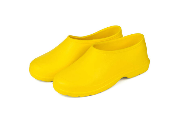 Пара ярко-желтых галош, выделенных на белом фоне. Обувь для дождливой погоды. - Фото, изображение