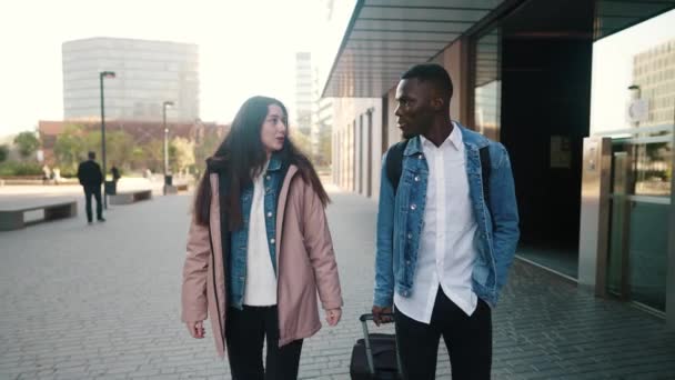 Couple itinérant multiracial avec bagage marchant en ville - Séquence, vidéo