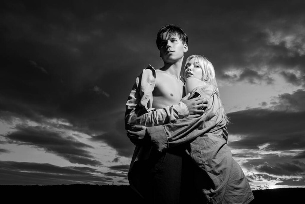 Young couple in love hug each other on dramatic sky. Love story. - Fotografie, Obrázek