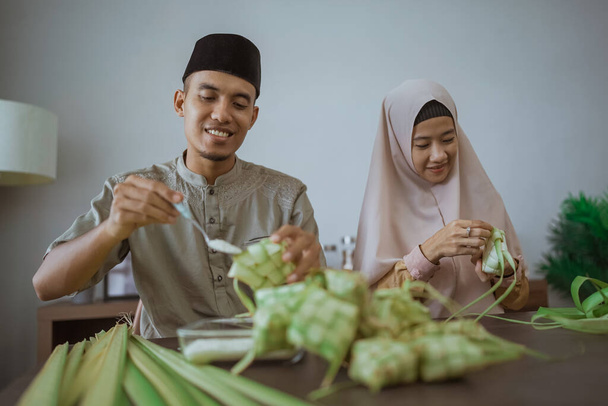 muslim couple asian making ketupat rice cake at home using palm leaf - Foto, Bild