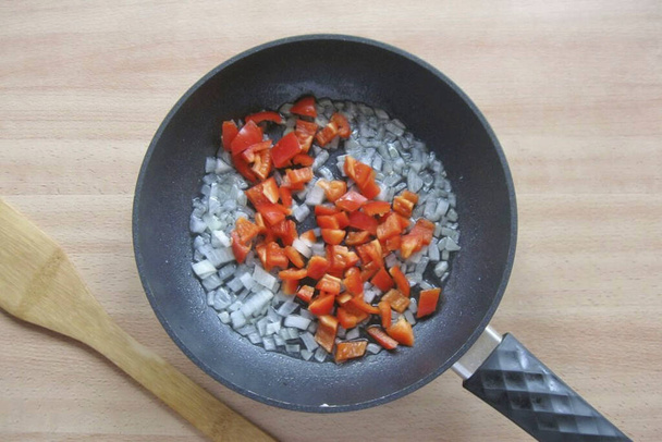 Peel the Bulgarian pepper from seeds, wash and finely chop. Add to onion. - Fotó, kép