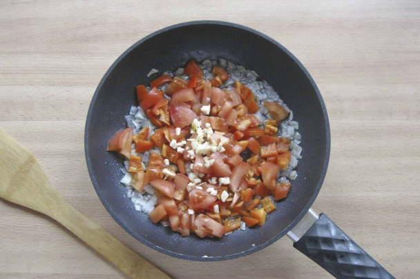 Add finely chopped garlic to the pan. - Фото, изображение