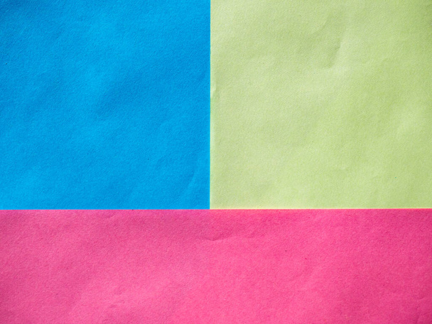 Φύλλα από πορφυρό, κίτρινο και μπλε χαρτί βρίσκονται το ένα πάνω στο άλλο και σχηματίζουν τετράγωνα και ένα ορθογώνιο. Αφηρημένο γεωμετρικό υπόβαθρο με τρεις πολύχρωμους τομείς. - Φωτογραφία, εικόνα