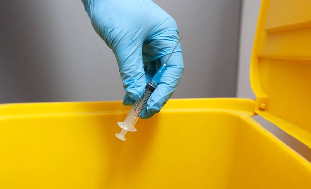 The nurse throw away used syringe into bin - Фото, изображение