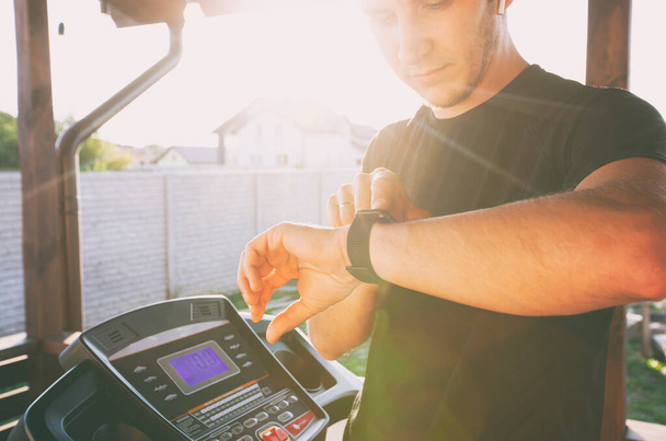 Guy is starting training on treadmill and launching fitness application on his smartwatches - Fotoğraf, Görsel