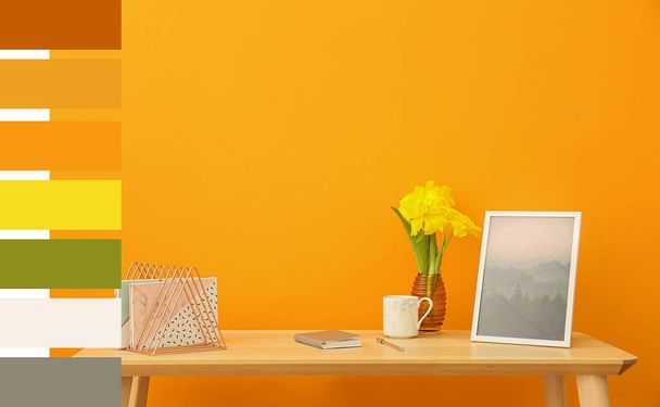 Stílusos munkahely gyönyörű virágokkal, csésze kávé és notebook a színes fal közelében. Különböző színű minták - Fotó, kép