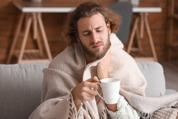 Ill man with sore throat drinking hot tea at home - Фото, зображення