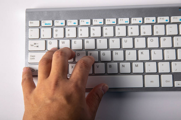 Крупный план Мужской палец на белой клавиатуре изолирован на белом фоне - Фото, изображение