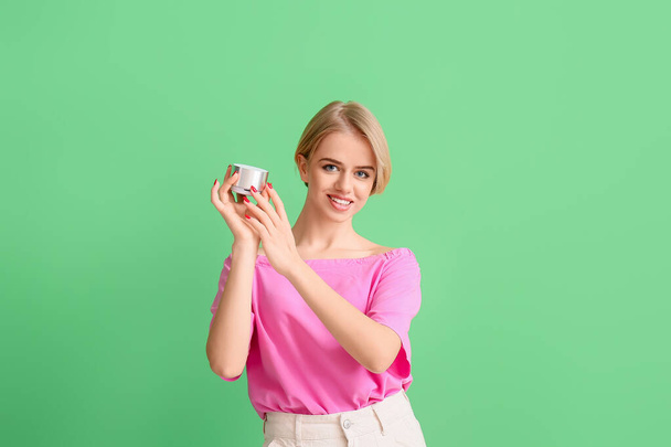 Beautiful smiling woman holding wireless portable speaker on green background - Photo, Image