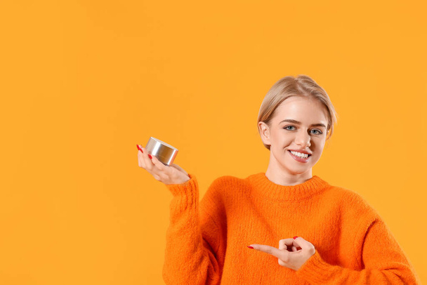 Jovem mulher sorridente apontando para alto-falante portátil sem fio no fundo de cor - Foto, Imagem