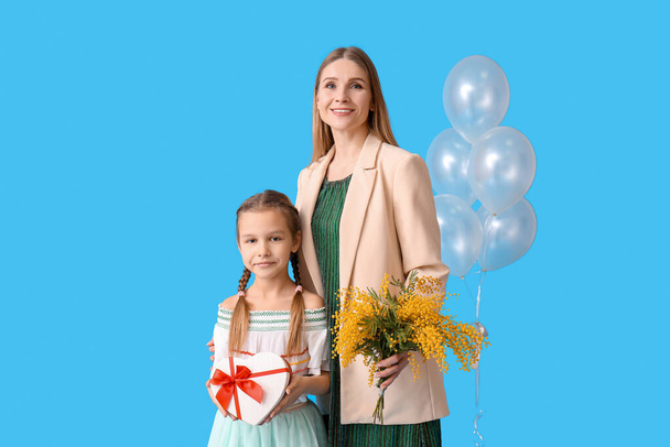 Little girl with her mother and gifts on blue background - Photo, Image