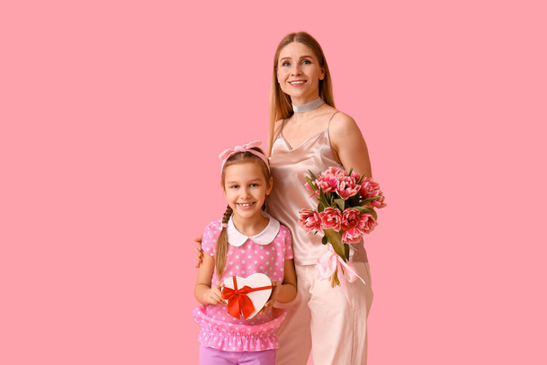 Little girl, her mother with tulips and gift on pink background - Photo, Image