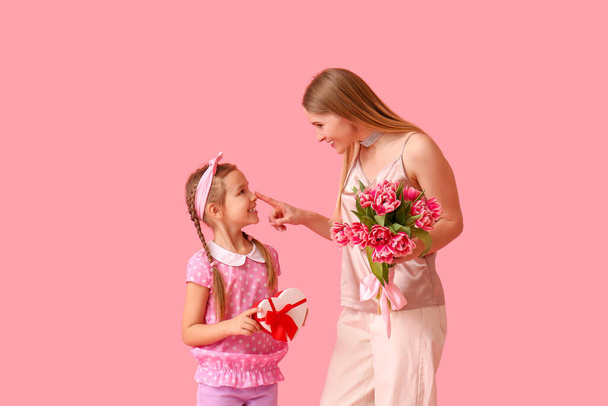 Petite fille, sa mère avec des tulipes et un cadeau sur fond rose - Photo, image