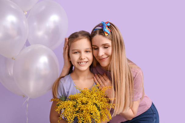 Little girl, her mother with flowers and balloons on lilac background - Photo, Image