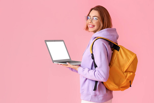 Female student with laptop on pink background - Fotoğraf, Görsel