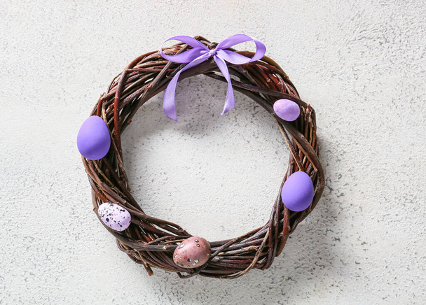 Beautiful wreath with Easter eggs on light background - 写真・画像