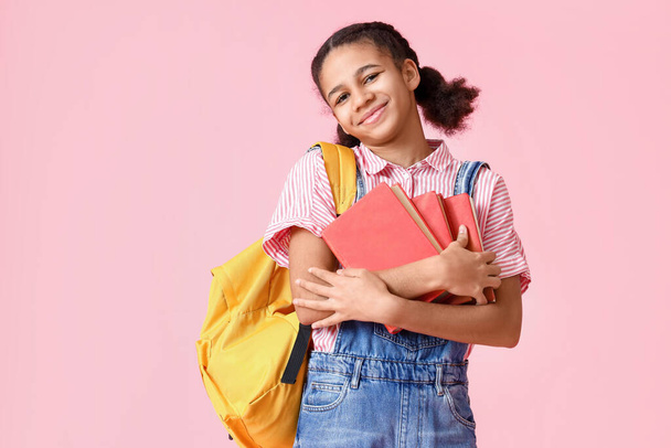 Afro-Amerikaanse studente met boeken over roze achtergrond - Foto, afbeelding