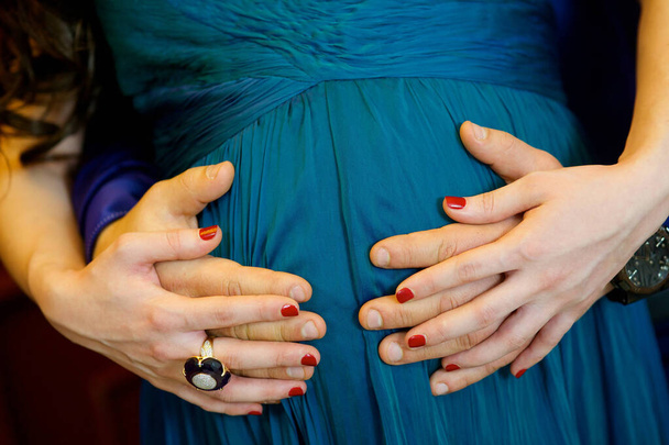Female the hands of the mother and male father's hand holding the belly, inside of which a baby. - Zdjęcie, obraz
