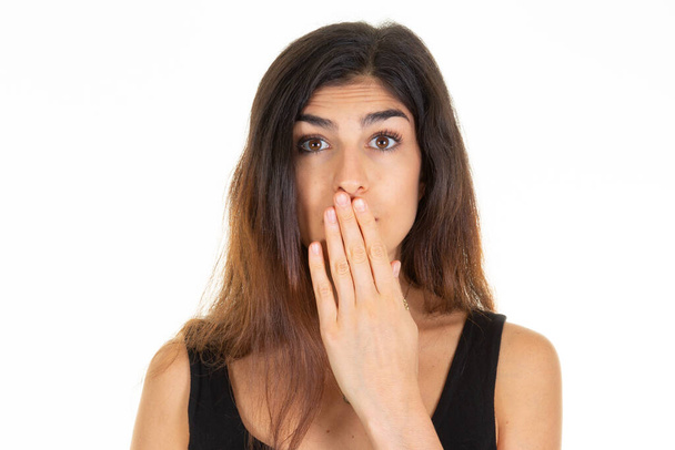 όμορφη γυναίκα καλύπτουν το στόμα με τα δάχτυλα των χεριών με σοκαρισμένη έκφραση λέγοντας ουπς σε λευκό φόντο - Φωτογραφία, εικόνα