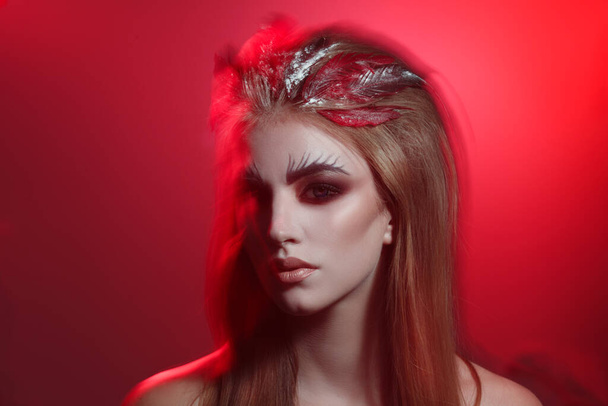 Sensual portrait of a pretty girl with creative makeup on a red background. - 写真・画像