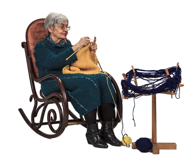 Image of an old woman sitting on a rocker and knitting, isolated against a white background. - Photo, image