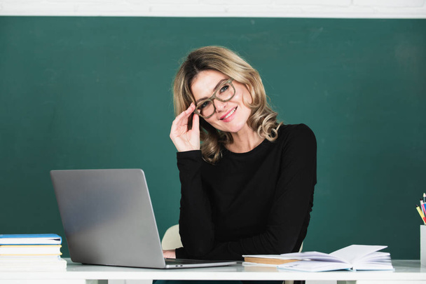 Smiling girl student or woman teacher portrait on green blackboard in classroom at collage. - Fotó, kép