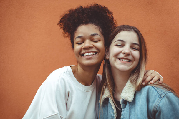 Portrait of two happy joyful teen girls of different races smiling at camera, enjoying friendship, multi-ethnic best female friends making selfie photo and having fun while spending time together - Foto, Bild