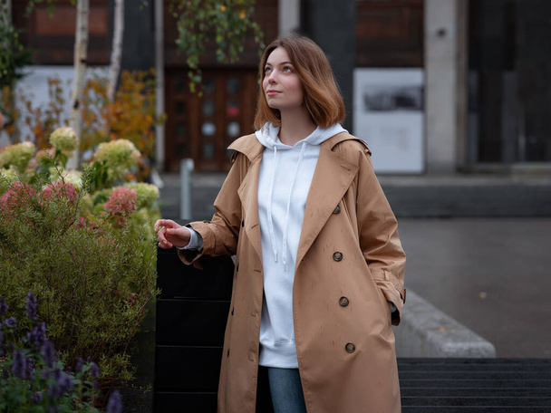美しいベージュのコートで美しい女性は秋の曇りモスクワ、レーニン図書館で歩く。ストリートスタイル。ロシアの概念への旅行. - 写真・画像