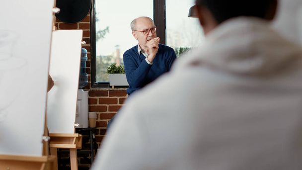 Homem sênior ensinando estudantes de arte a desenhar obras de arte em tela - Foto, Imagem