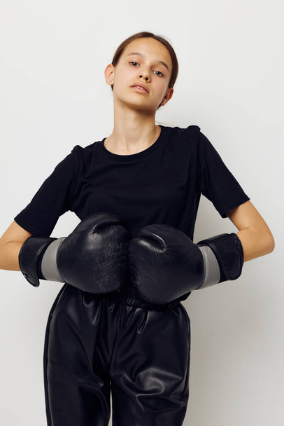 young beautiful woman in boxing gloves in black pants and a T-shirt light background - Foto, Imagen