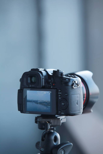 фотокамера, смонтированная на штативе в процессе съёмок видео с заднего вида крупным планом - Фото, изображение