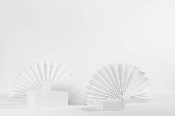 Λευκό μαλακό φως αφηρημένη σκηνή με το σύνολο των τριών διαφορετικών μέγεθος ορθογώνιο podiums πρότυπο για την επίδειξη καλλυντικών προϊόντων ή αγαθών με στρογγυλό ανατολίτικο ανεμιστήρες χαρτιού, πλευρική άποψη, γωνία, 3d, αντίγραφο χώρου. - Φωτογραφία, εικόνα