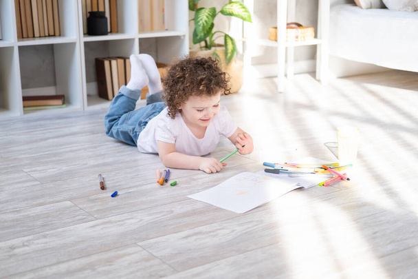 kręcone dziecko dziewczyna rysunek kolorowe markery leżące na podłodze w salonie w domu - Zdjęcie, obraz