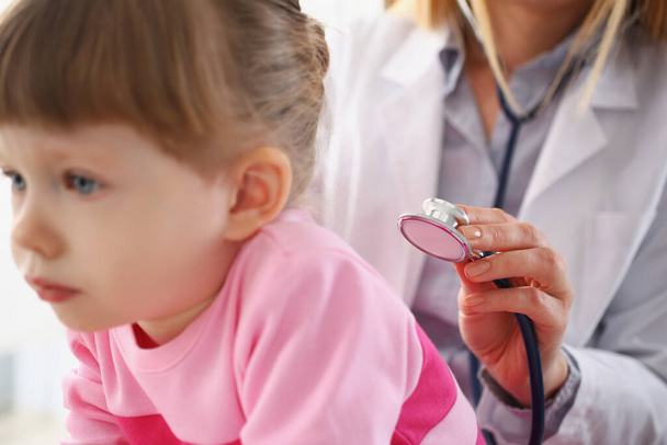 Kleines Mädchen wird vom Kinderarzt untersucht, ruhiges Kind wartet geduldig auf Termin - Foto, Bild